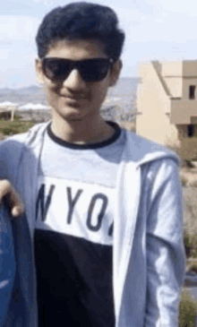 a young man wearing sunglasses and a nyc shirt .