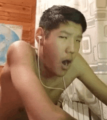 a shirtless man wearing ear buds is making a funny face .