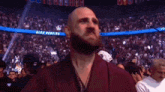 a bald man with a beard stands in front of a crowd in a stadium with a banner that says alex pereira .