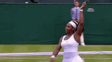 a tennis player is waving her hand in the air while holding a tennis racquet on a tennis court .