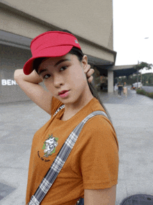 a woman wearing a red visor stands in front of a ben sign