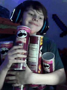 a young boy wearing headphones is holding a can of pringles bbq