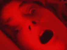 a close up of a person 's face with a red light behind them .