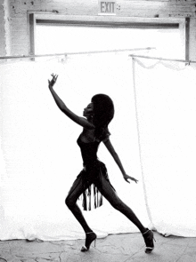 a woman is dancing in front of a white exit sign