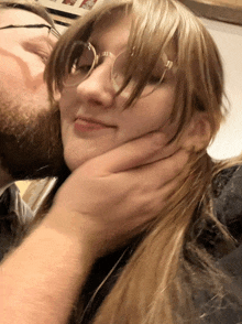 a woman with glasses is being kissed by a man