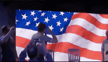 a man salutes in front of an american flag on a screen