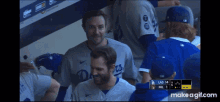 a group of baseball players are sitting in a dugout and one of them has the letter d on his shirt