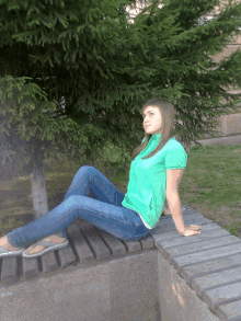 a girl in a green shirt is sitting on a bench