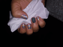 a woman 's nails are painted in different colors and she is holding a napkin