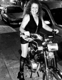 a woman is riding a motorcycle on the sidewalk next to a car .