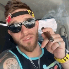 a man wearing sunglasses and a headband is smoking a cigar .