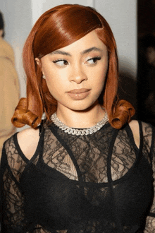 a woman with red hair wearing a black lace top and a necklace