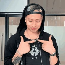 a man wearing a hoodie is pointing at a necklace