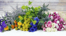 a bunch of different colored flowers on a white table