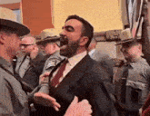 a man in a suit and tie is standing in front of a group of police officers ..