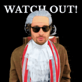 a man wearing a wig and sunglasses is sitting in front of a sign that says watch out