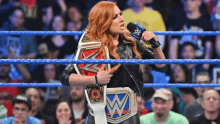 a woman in a wrestling ring is holding a wwe championship belt