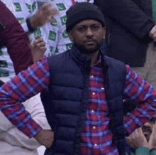 a man wearing a plaid shirt and a black vest