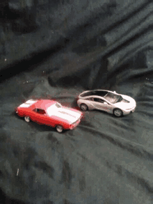 a red car and a white car on a black surface