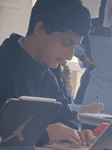 a boy sits at a desk with a tablet and a pen in his hand