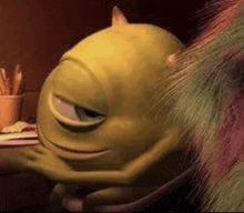 mike wazowski from monsters inc is sitting at a desk hugging a monster .