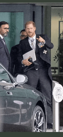 a man in a suit and tie is standing next to a green car