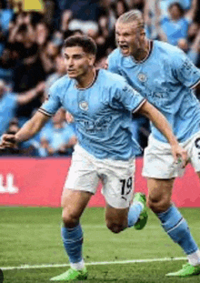 two soccer players wearing blue jerseys with the number 19 on them