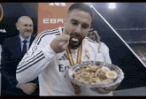 a man with a medal around his neck eating a plate of food