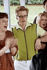 a man wearing glasses and a green jacket is surrounded by women