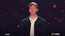 a man stands in front of a blue background with a nbc logo on it