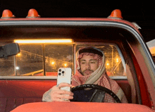 a man in a keffiyeh is taking a selfie in the back of a truck