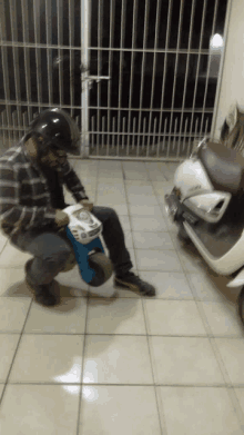 a man wearing a helmet is kneeling down next to a small toy scooter