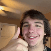 a young man smiles and gives a thumbs up sign