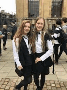 two girls are posing for a picture in front of a building .