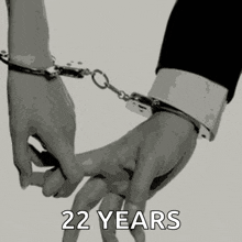 a man and woman are holding hands with handcuffs on their wrists .