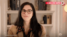 a woman wearing glasses is smiling in front of a bookshelf with a red sign that says red nose day .