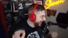 a man wearing headphones and glasses is sitting in front of a microphone .