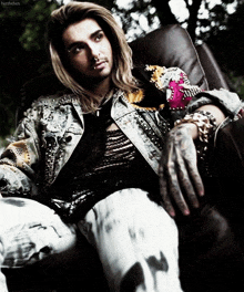 a man with long hair and a nose ring is sitting on a chair