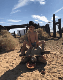 a boy in a cowboy hat is sitting on a turtle