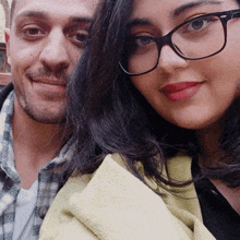 a man and a woman are posing for a picture and the woman has glasses on