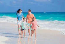 a family is walking on the beach holding hands and wearing sunglasses