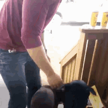 a man in a maroon shirt is standing in front of a wooden table with two cans of beer on it