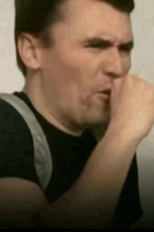 a man is covering his mouth with his hand and making a funny face