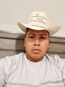 a man wearing a cowboy hat and a grey shirt looks at the camera