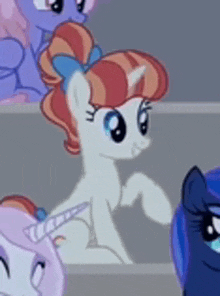 a group of ponies are standing next to each other and one of them has a bow in her hair .