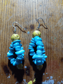 a pair of blue and yellow earrings on a wooden table