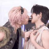 a man with pink hair kissing another man with black hair