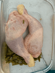 a chicken leg is sitting in a clear container with green beans