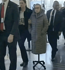 a woman in a grey coat is standing on a small office chair