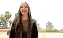 a woman with long hair is smiling and standing in front of a wall .